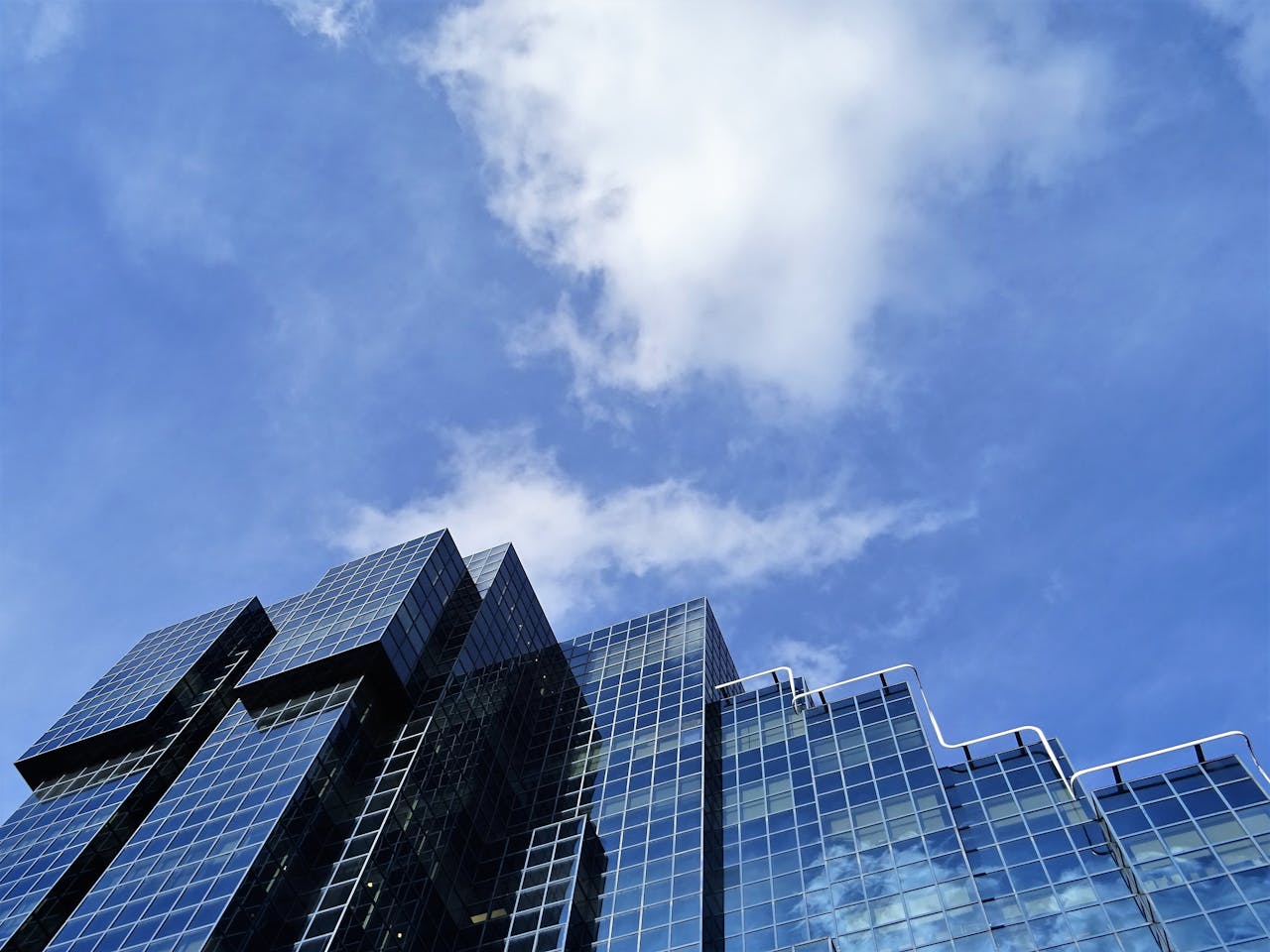 Low angle view of a modern skyscraper with glass windows reflecting the sky.