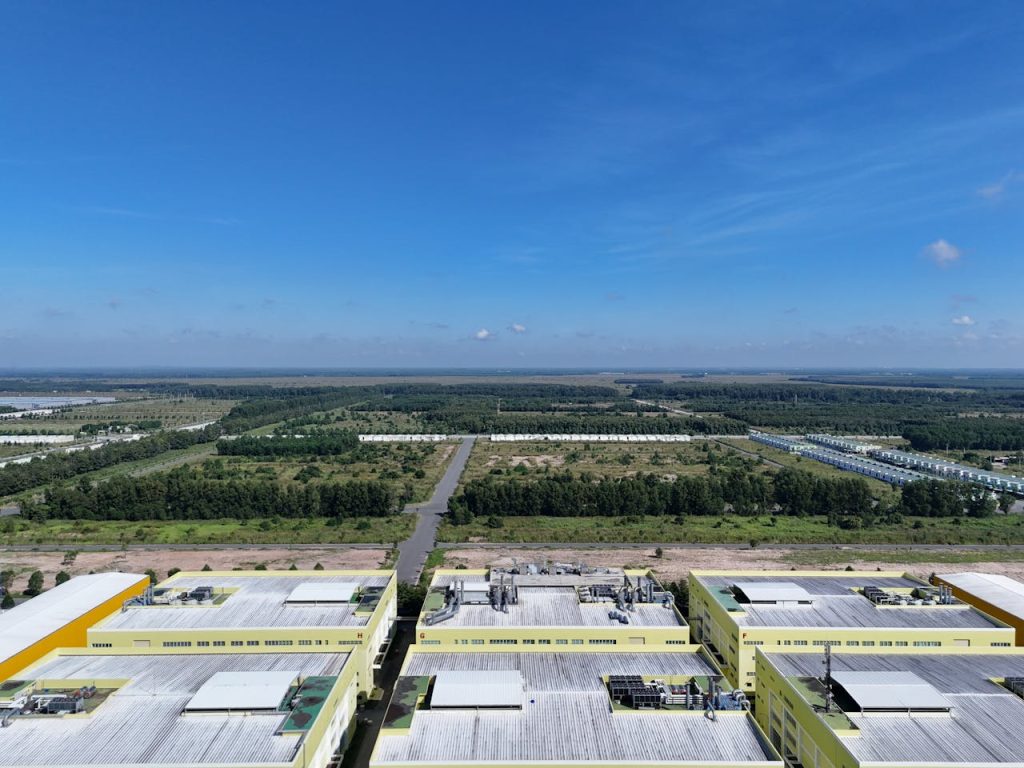 Aerial shot of industrial buildings and green landscape in Bình Dương, Vietnam under a clear blue sky.