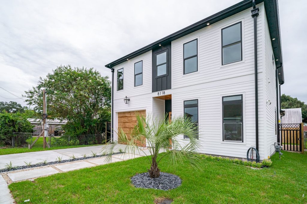 Modern two-story house in New Orleans with a lush green lawn and contemporary design.